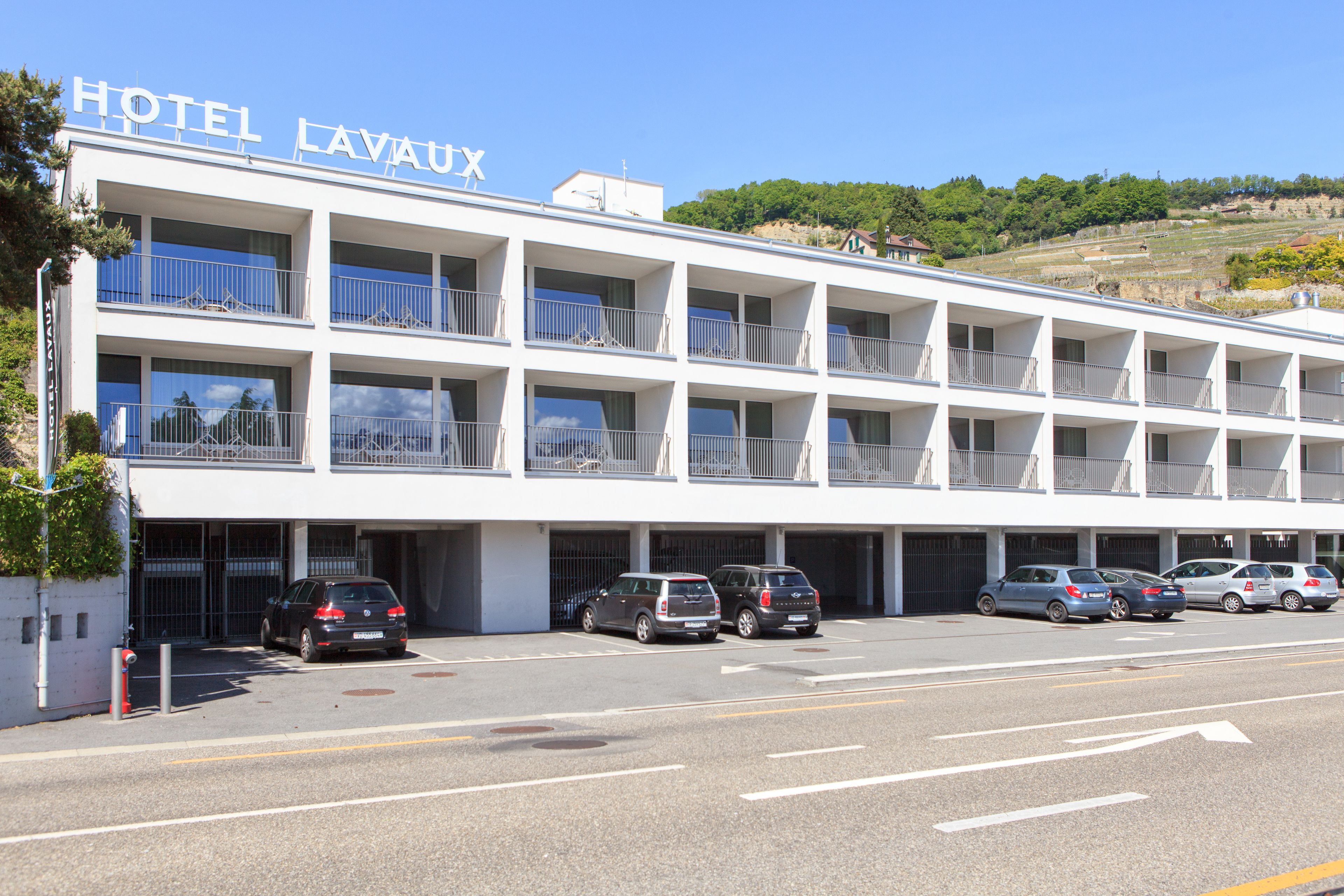 Un hotel de varios pisos con balcones y un estacionamiento.