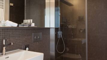 Un baño moderno con lavamanos blanco, inodoro y ducha con mampara de vidrio.