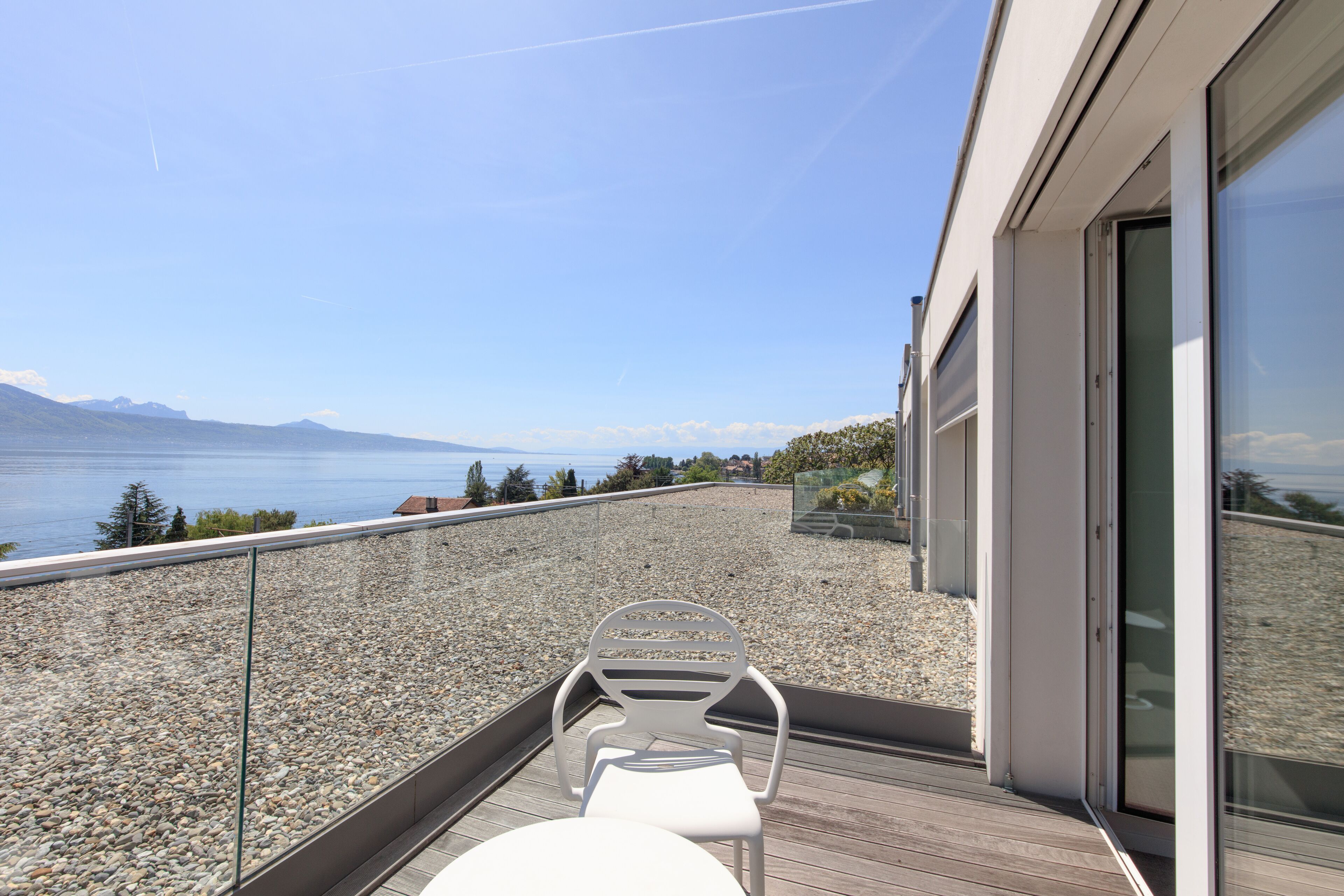 Un balcón con vista al mar, una silla y una mesa.