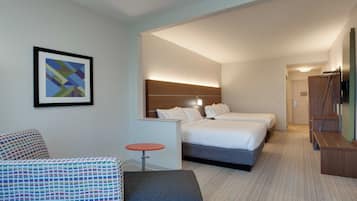 Quarto de hotel com cama, mesas de cabeceira, mesa redonda pequena, sofá e quadro na parede.