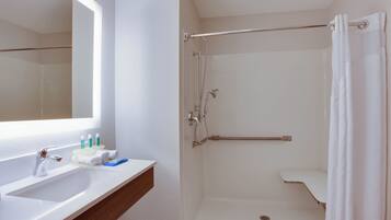 A bathroom with a white sink, mirror, and shower.