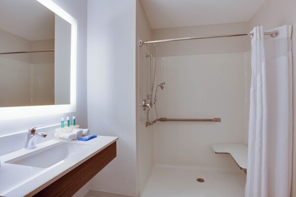 A bathroom with a white sink, mirror, and shower. - Holiday Inn Express Orlando International Airport by IHG (Orlando)