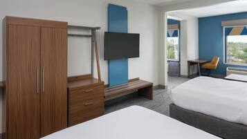 Habitación de hotel moderna con una cama grande, un armario de madera, un televisor de pantalla plana y un pequeño escritorio con una silla.