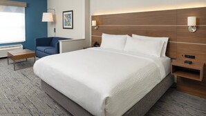 Una habitación de hotel con una cama grande, un escritorio, una silla y una lámpara de pared.
