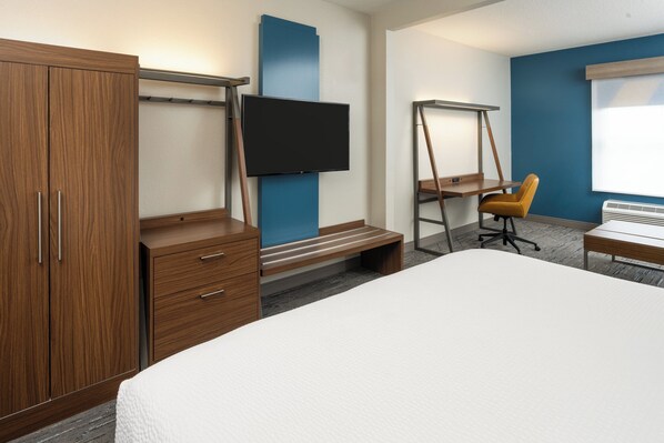 A hotel room with a large bed, wooden wardrobe, a desk with a chair, a TV mounted on the wall, and a window. - Holiday Inn Express Orlando International Airport by IHG (Orlando)