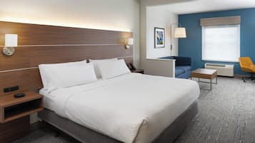 Una habitación de hotel con una cama grande, mesitas de noche, un escritorio, una silla y una ventana con persianas.