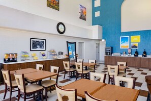 Enjoy meals in a spacious dining area with a high ceiling, framed artwork, and classic wooden furniture.