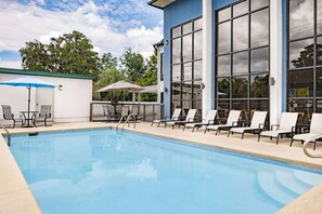 Relax by the pool surrounded by lush greenery and comfortable lounge chairs.