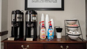 A coffee station with two coffee makers, disposable cups, and coffee creamer bottles. - Red Roof Inn & Suites Newnan (Newnan)