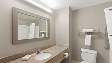 A bathroom with a granite countertop, a white sink, a mirror, a towel rack, and a toilet.