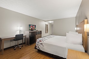 A hotel room with a bed, desk, chair, and a television. - Red Roof Inn & Suites Newnan (Newnan)