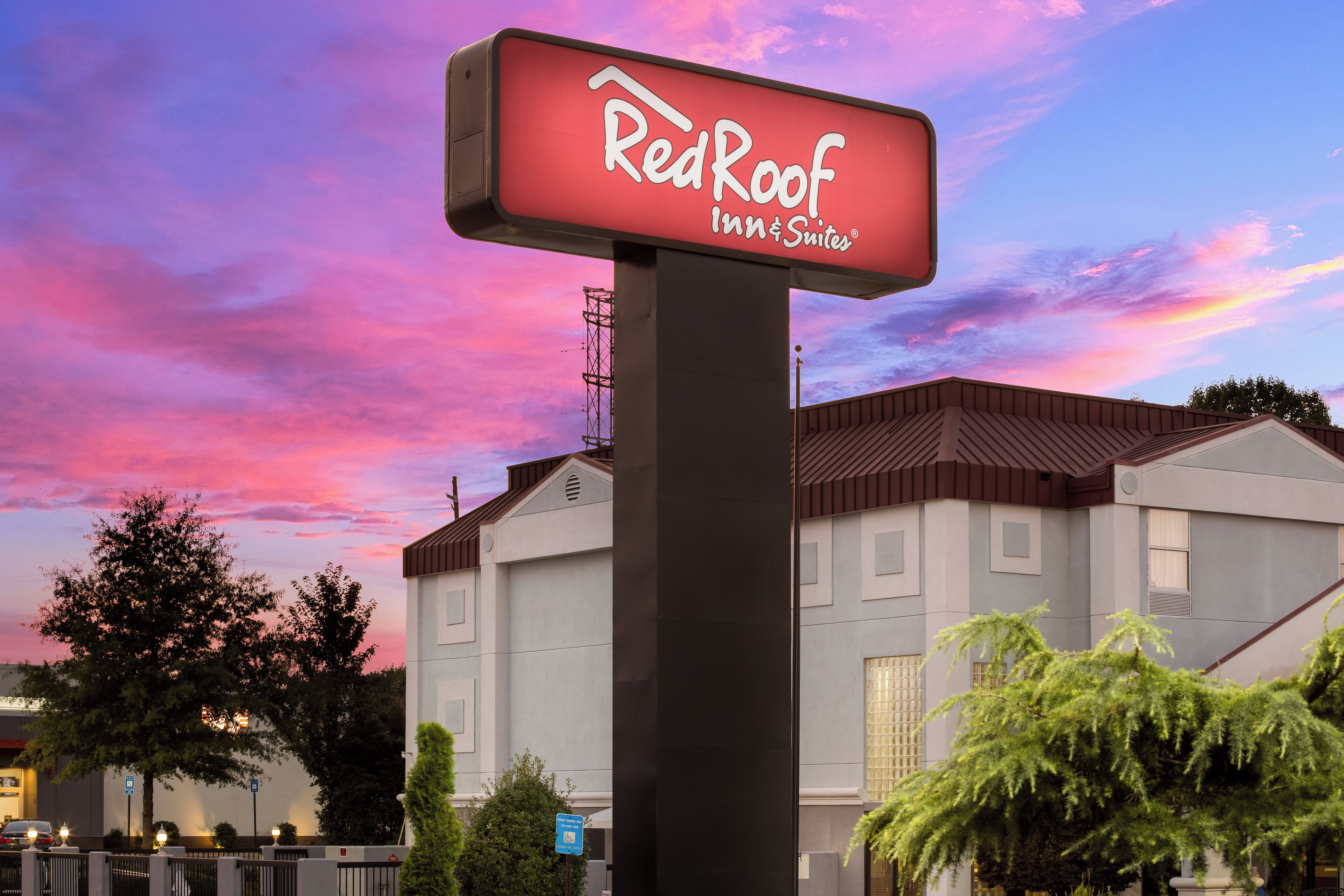 Un letrero de Red Roof Inn & Suites con un edificio moderno al fondo.