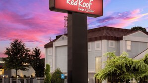 A Red Roof Inn & Suites sign with a modern building in the background. - Red Roof Inn & Suites Newnan (Newnan)
