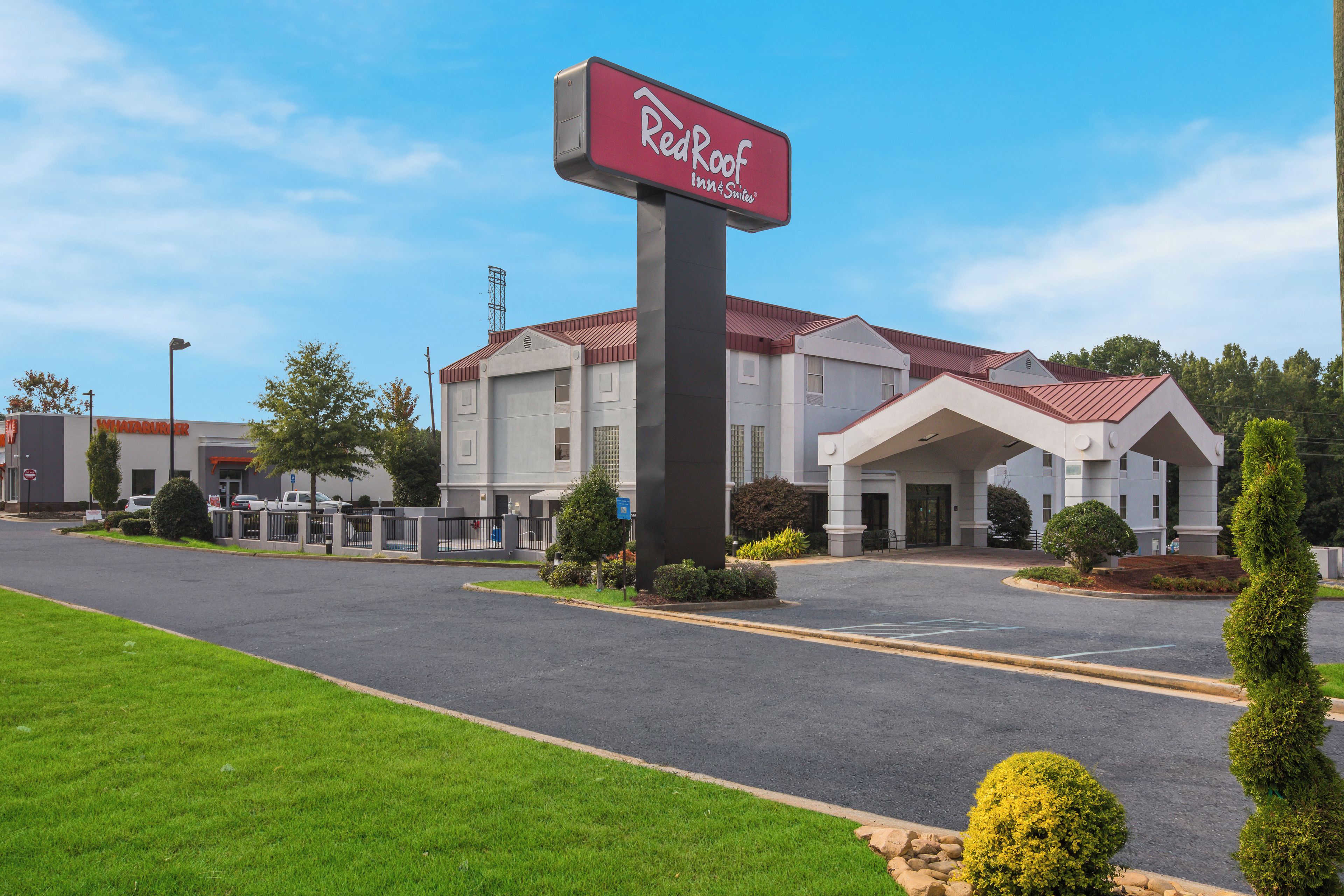 A Red Roof Inn & Suites with a parking lot and a building with a red roof.