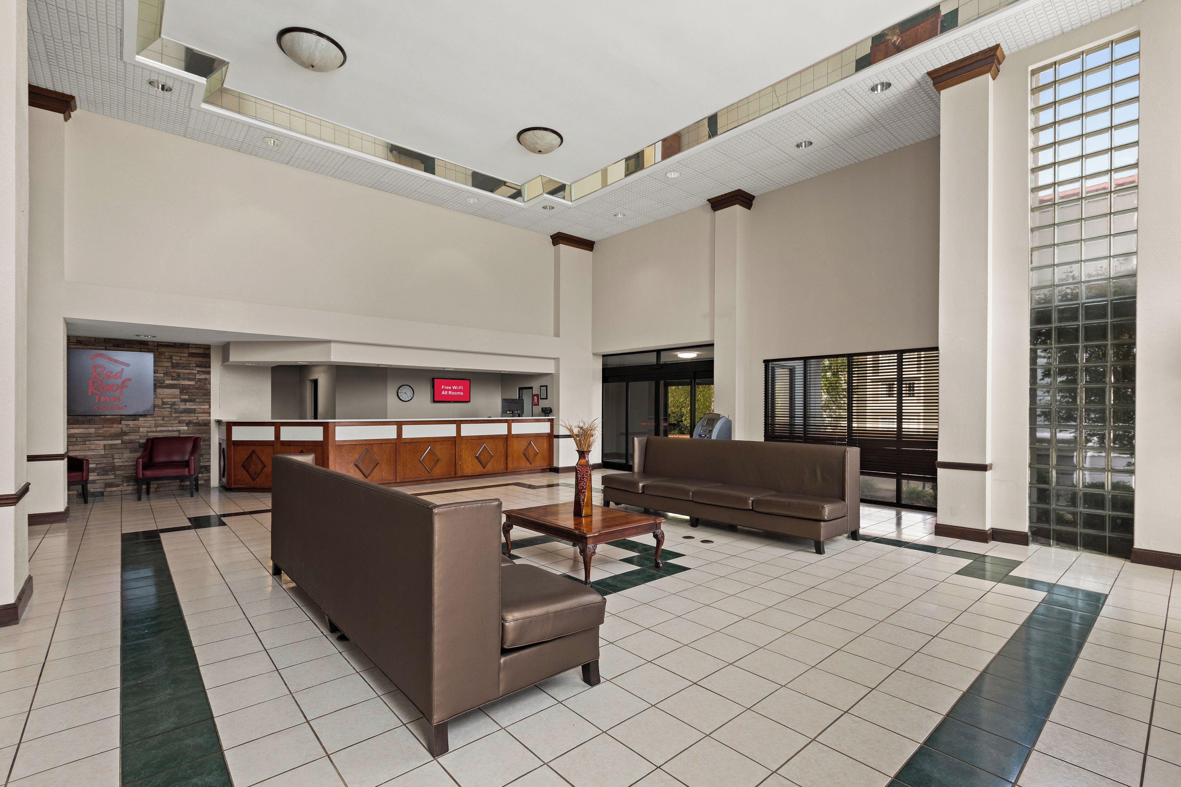 A spacious lobby with a reception desk, seating area, and a large window providing natural light.