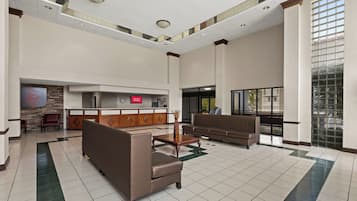 A spacious lobby with a reception desk, seating area, and a large window providing natural light.