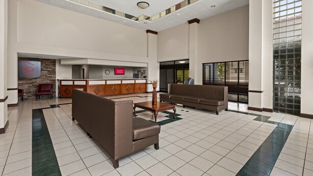 A spacious lobby with a reception desk, seating area, and a large window providing natural light.