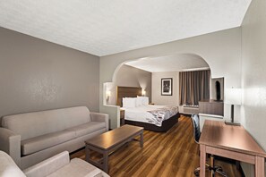 A hotel room with a sofa, a bed, a desk, and a wooden floor. - Red Roof Inn & Suites Newnan (Newnan)