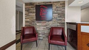 A reception area with a stone wall, two leather chairs, and a sign reading 'Red Rock Inn & Suites'. - Red Roof Inn & Suites Newnan (Newnan)