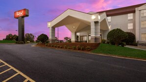 A hotel with a large sign, a covered entrance, and a parking lot.