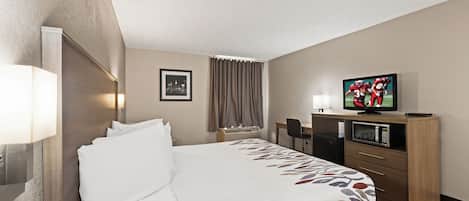 A hotel room with a bed, a desk, a television, and a microwave.