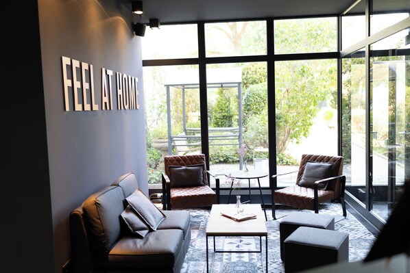 Relax in a cozy lounge area with a garden view, comfortable seating, and a warm atmosphere.