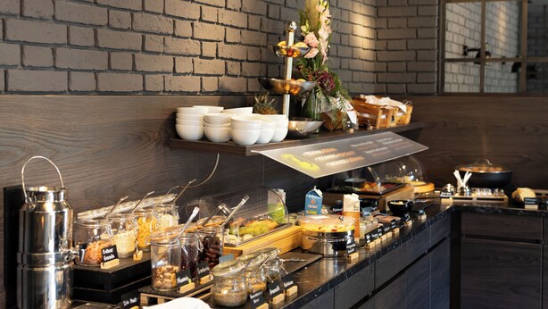 Montaje de bufé con diversos alimentos y una planta decorativa.