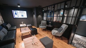 Un área de descanso moderna con sofás de cuero, sillas estampadas y una mesa de centro de madera.