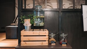 Una caja de madera con un tarro de vidrio de té de menta, un tarro de vidrio de galletas y un pequeño recipiente metálico sobre una mesa de madera oscura.