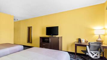 Una camera d'albergo con due letti, una scrivania con una sedia, una televisione, uno specchio e una lampada.