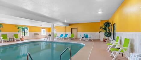 Una piscina interior con varias sillas reclinables y piso de baldosas.