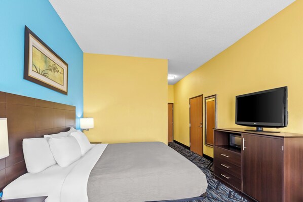 A hotel room with a bed, a television, a desk, and a painting on the wall.