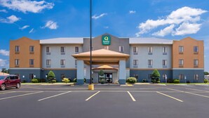 Ein Hotel mit zentralem Eingang, mehreren Stockwerken und einem Parkplatz.