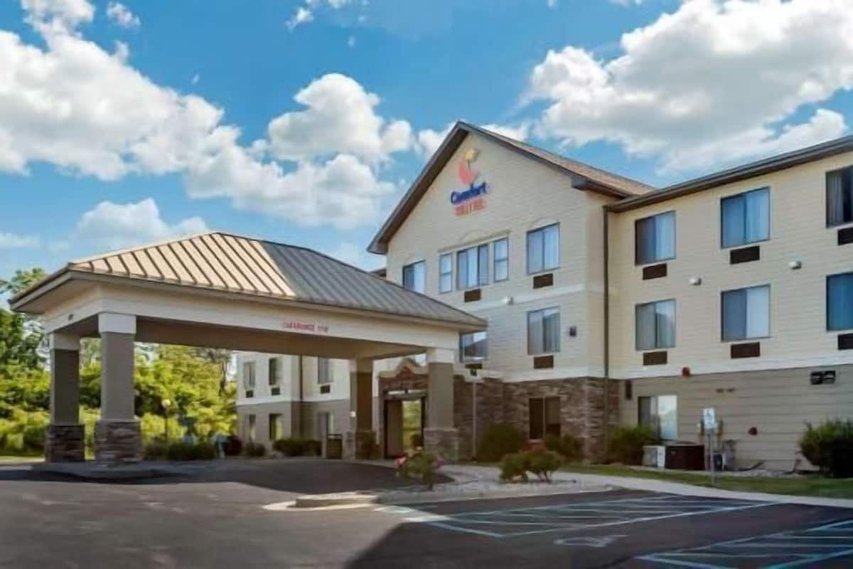 Un hotel con entrada techada, aparcamiento y cielo despejado.