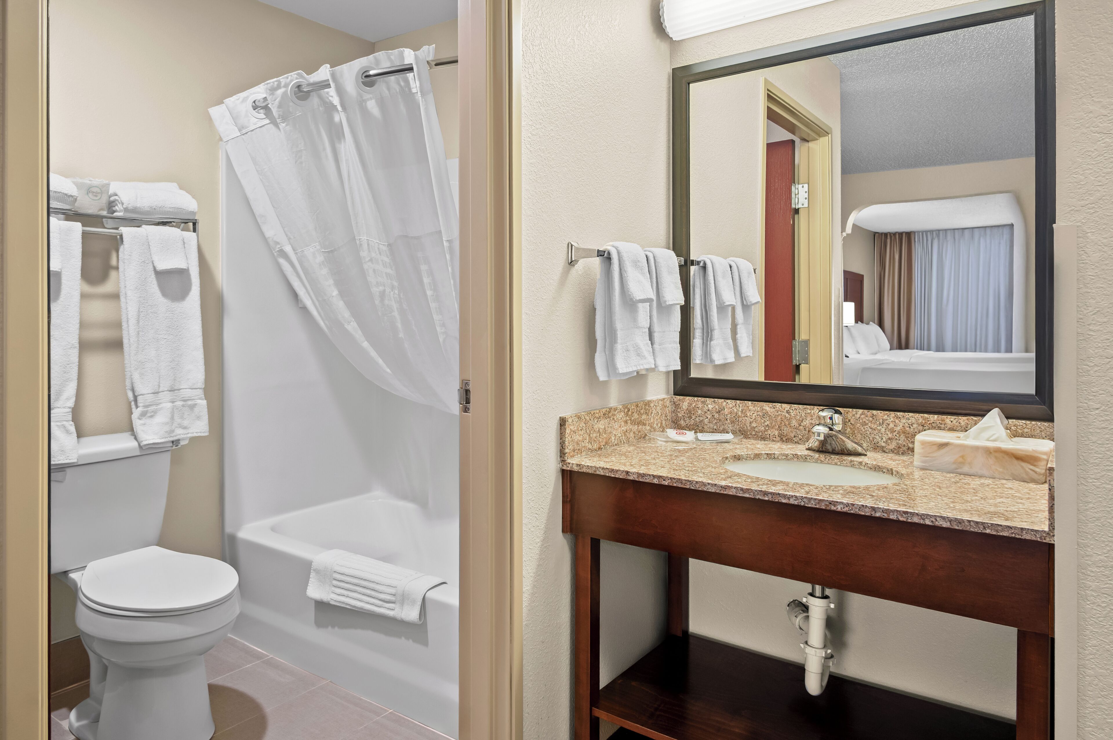 A bathroom with a toilet, a bathtub with a shower curtain, a sink with a mirror, and towels.