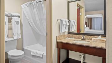 A bathroom with a toilet, a bathtub with a shower curtain, a sink with a mirror, and towels.