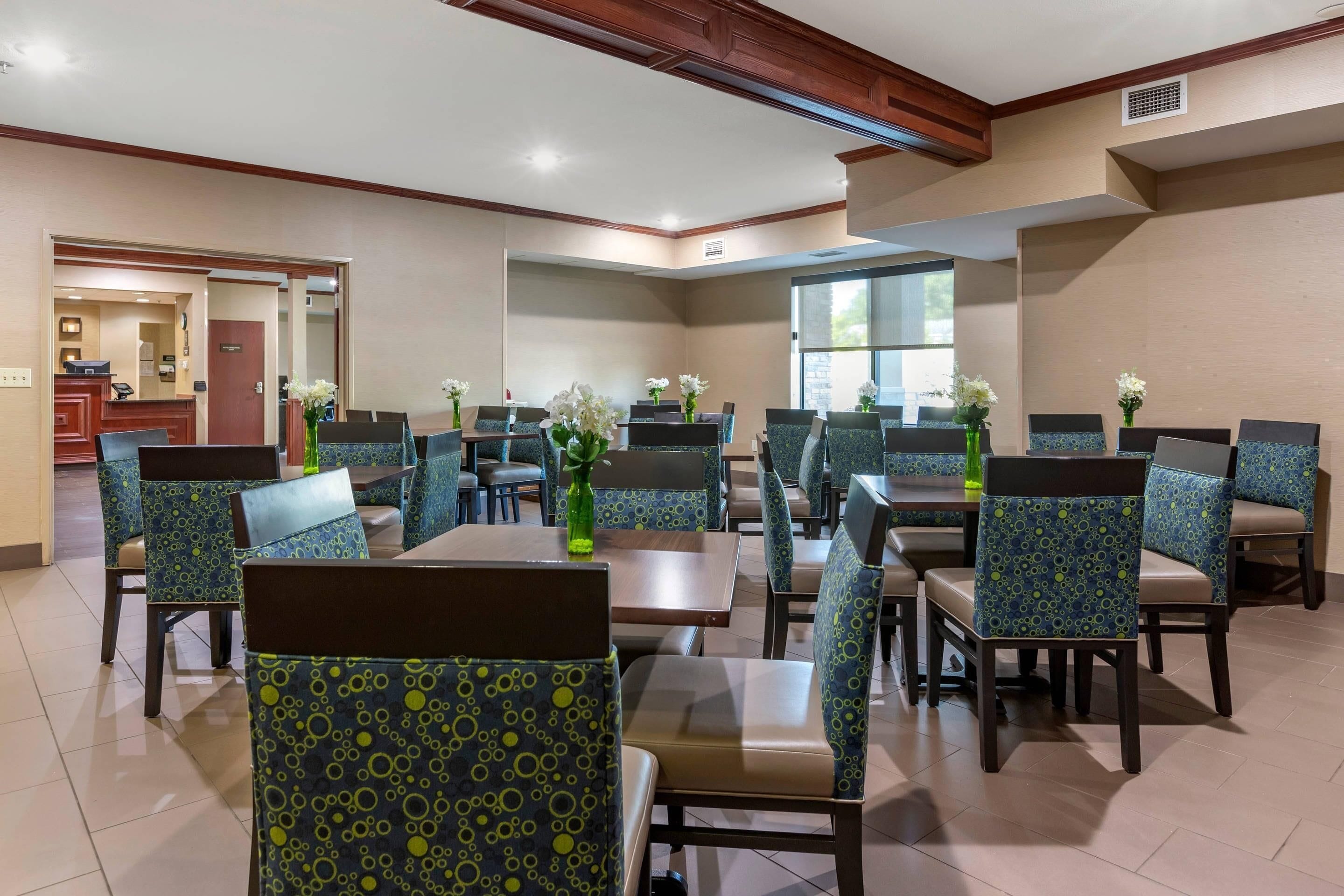 Un comedor de hotel con varias mesas y sillas, cada una con un centro de mesa floral.