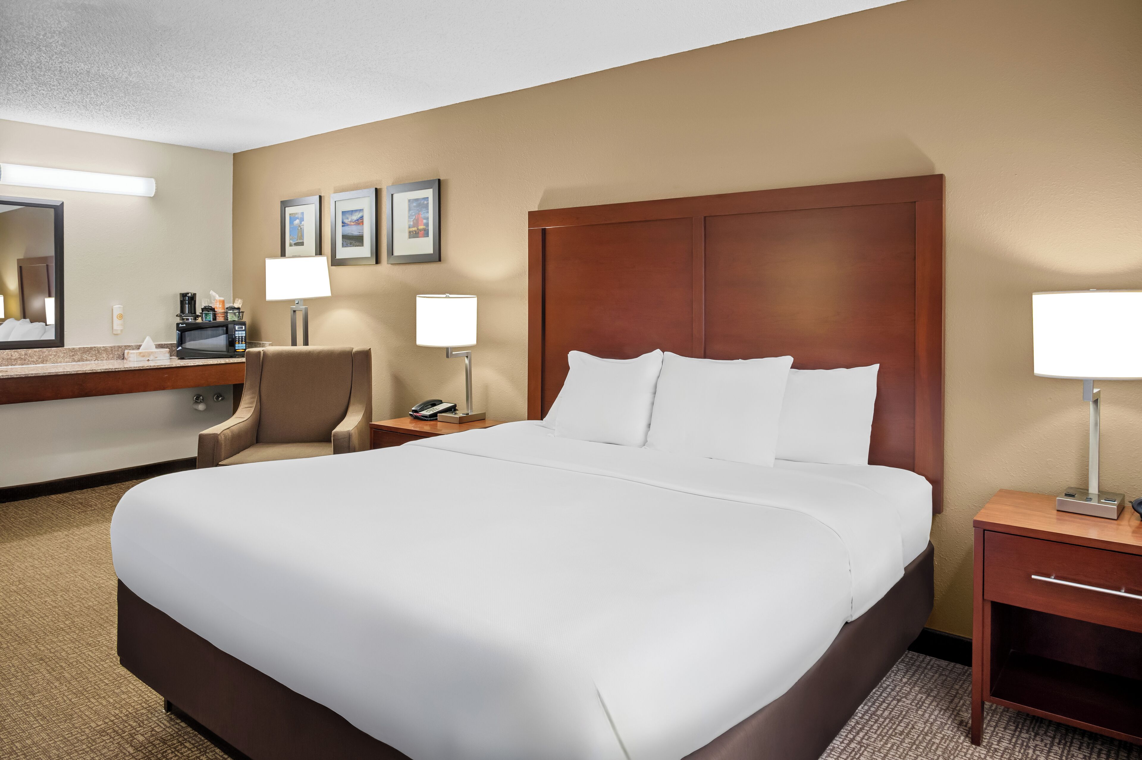 A hotel room with a large bed, a desk with a telephone, a chair, and a microwave.