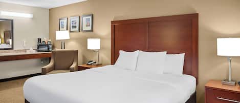 A hotel room with a large bed, a desk with a telephone, a chair, and a microwave.