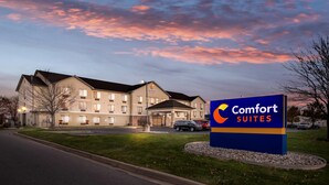 Un hotel Comfort Suites con un letrero, un estacionamiento y una carretera.