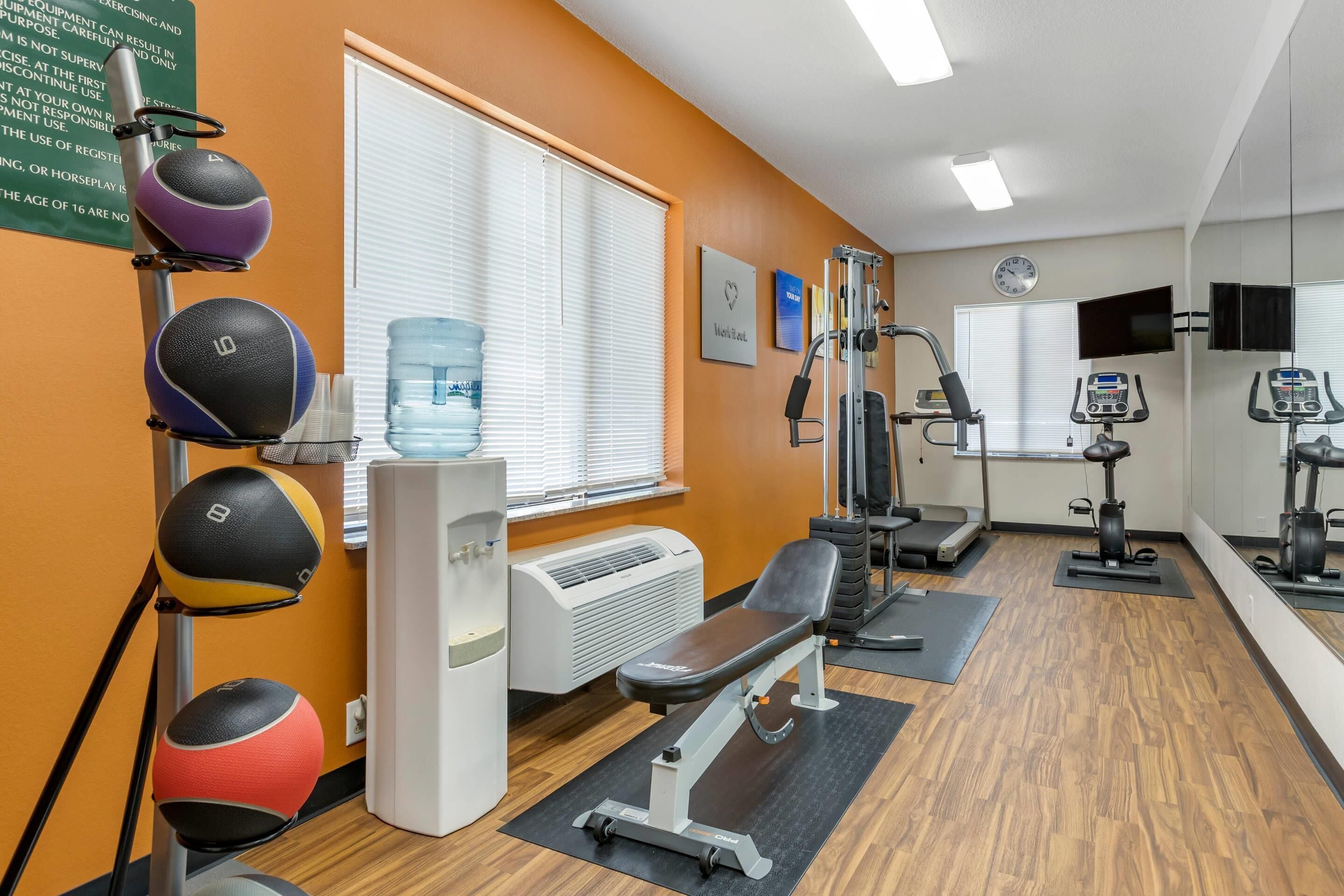 A gym with exercise equipment, a water cooler, and a bench.