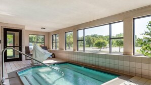 Una piscina con cerramiento de vidrio, ventanas amplias y vistas a árboles.