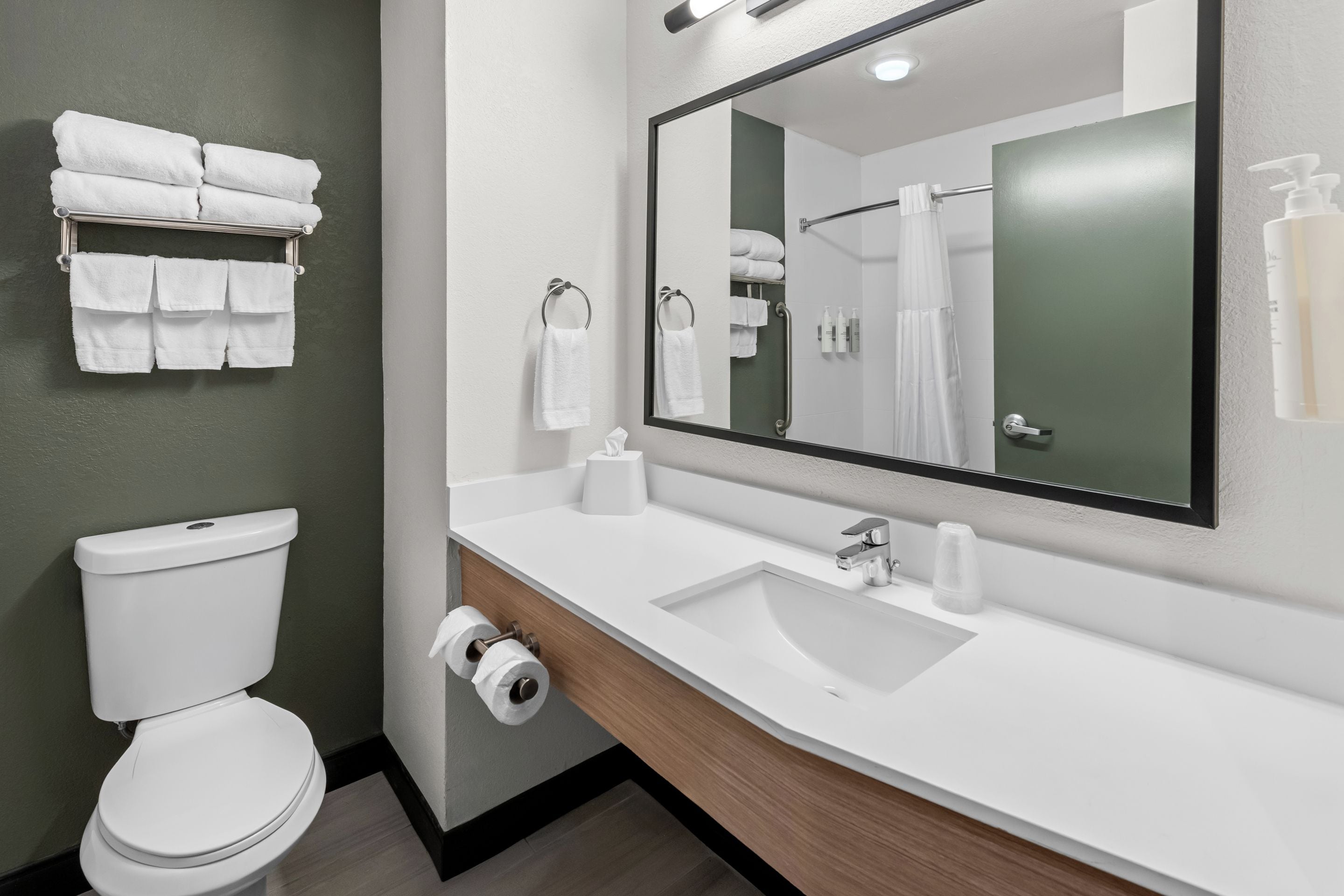 Un baño moderno con inodoro, lavamanos y espejo.