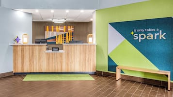 Um balcão de recepção com design moderno, uma parede verde com o letreiro 'spark' e um banco de madeira.