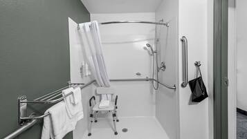A wheelchair-accessible shower with a grab bar, a towel rack, and a small step stool.