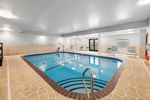 Ein Hallenbad mit klarem Wasser, einem Sprungturm und einem gefliesten Boden.