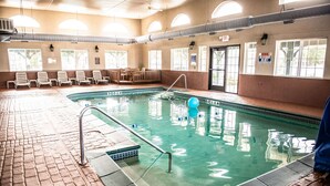 Une piscine à l’eau claire, avec un escalier et quelques chaises longues disposées autour de la piscine.