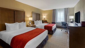 Une chambre d’hôtel avec deux lits, un bureau, une chaise, une lampe et un téléviseur.