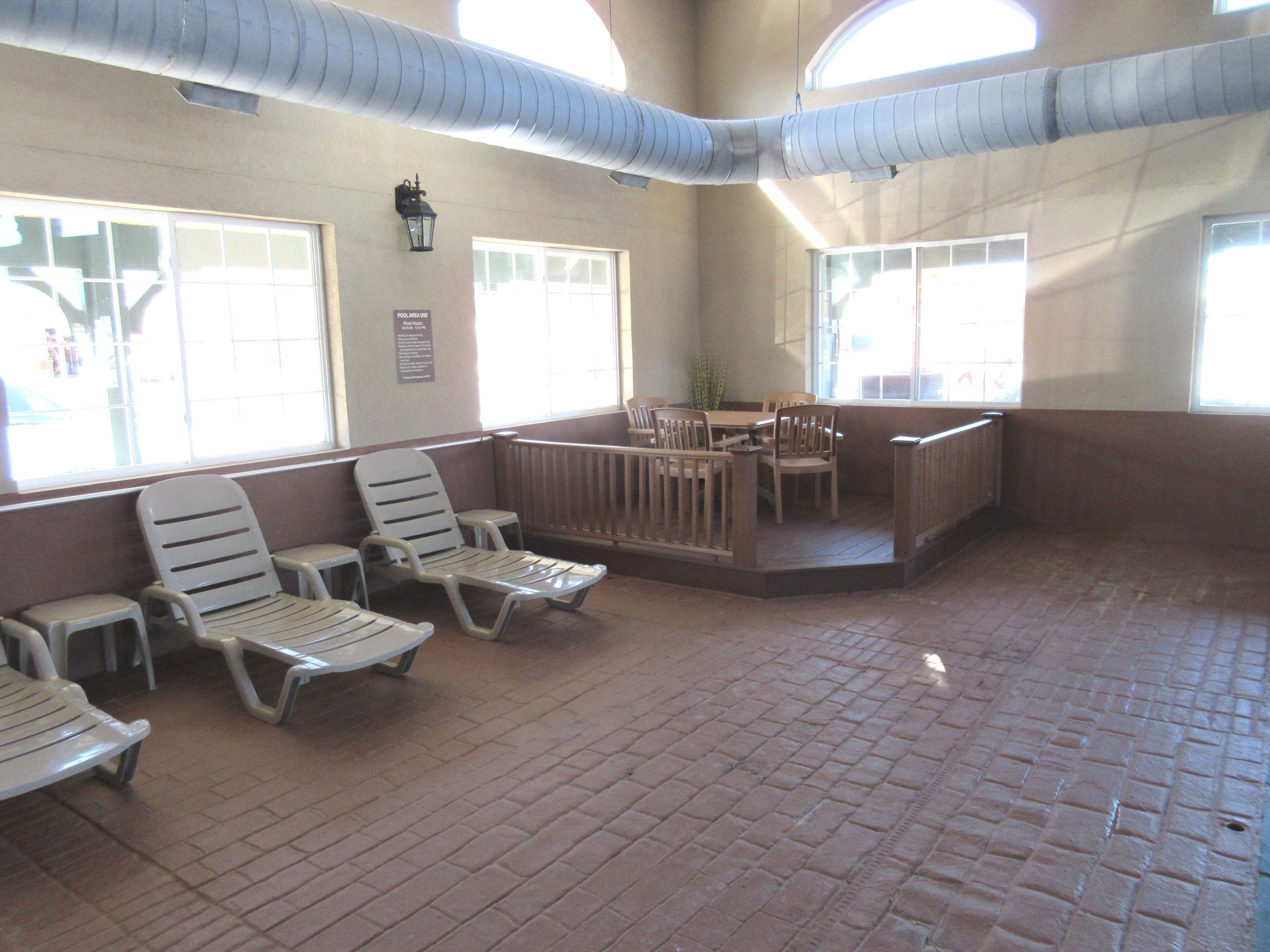 A sunlit indoor area with seating and a pool area view sign.