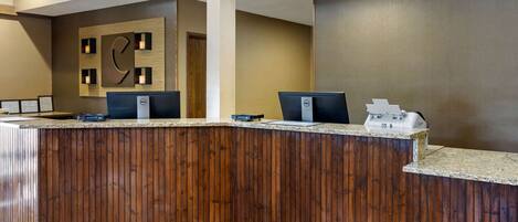 A reception area with a wooden reception desk, two computer monitors, and a reception counter.